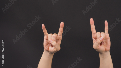 Male model is doing rock hand sign with two hands on blackground.