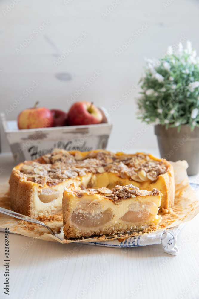 Bratapfelkuchen mit Äpfeln und Mandelblättchen auf hellem weißen Holzgrund