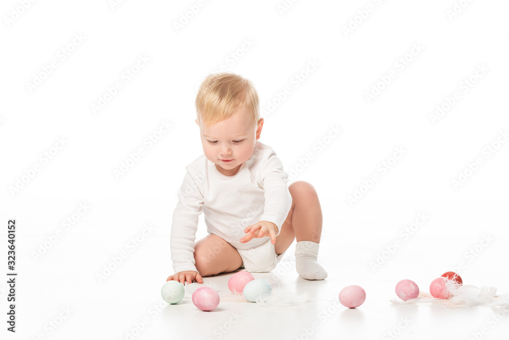 Cute child outstretching hand to easter eggs on white background