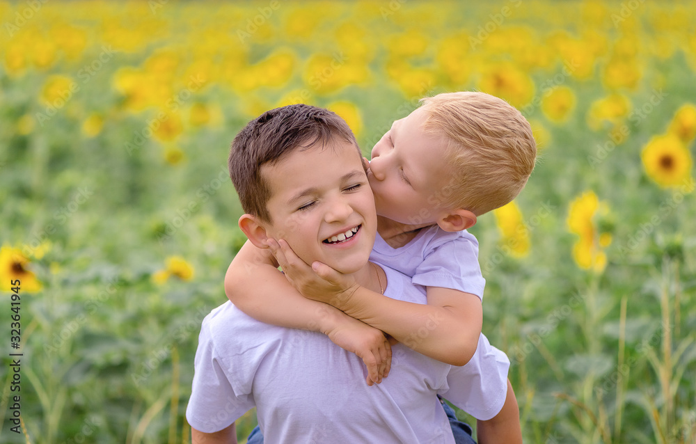 Fototapeta premium Two boys rother have fun in the field of sunflowers, summer, the concept of friendship