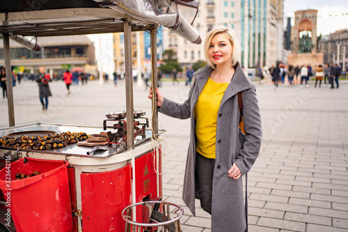 Photography Blonde girl on a tray with roasted chestnuts