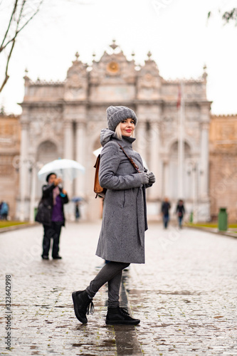 Blonde girl in coat and hat on the street in rain