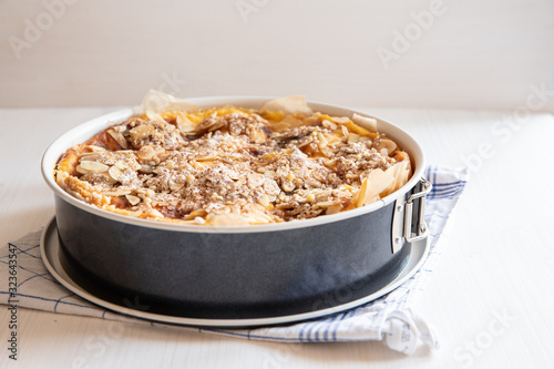ganzer Bratapfelkuchen in einer Backform auf hellem weißen Holzgrund mit Küchentuch