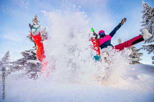 Happy team of snowboarders and skier having fun tossing snow. Light sun in winter forest sunrise