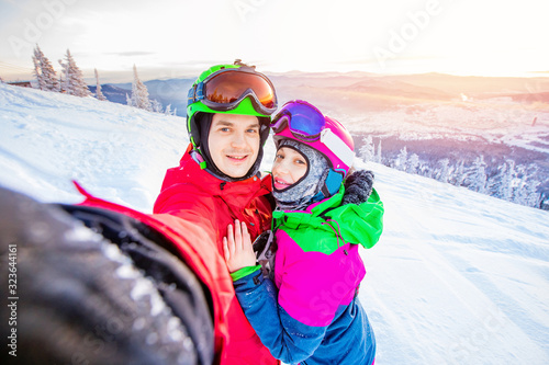 Team friends lover couple makes selfie photo of herself with snowboards and skis. Action camera