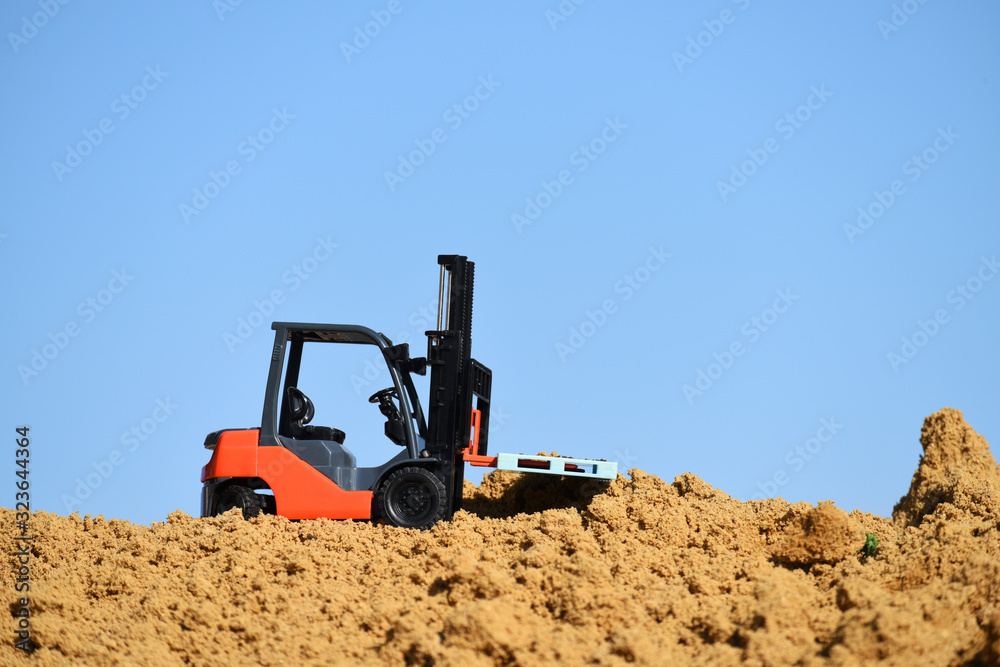Toy loader on a pile of sand against a blue sky. Loading and construction work. Sand quarry. Toy loader on a pile of sand against a blue sky. Loading and construction work. Sand quarry.