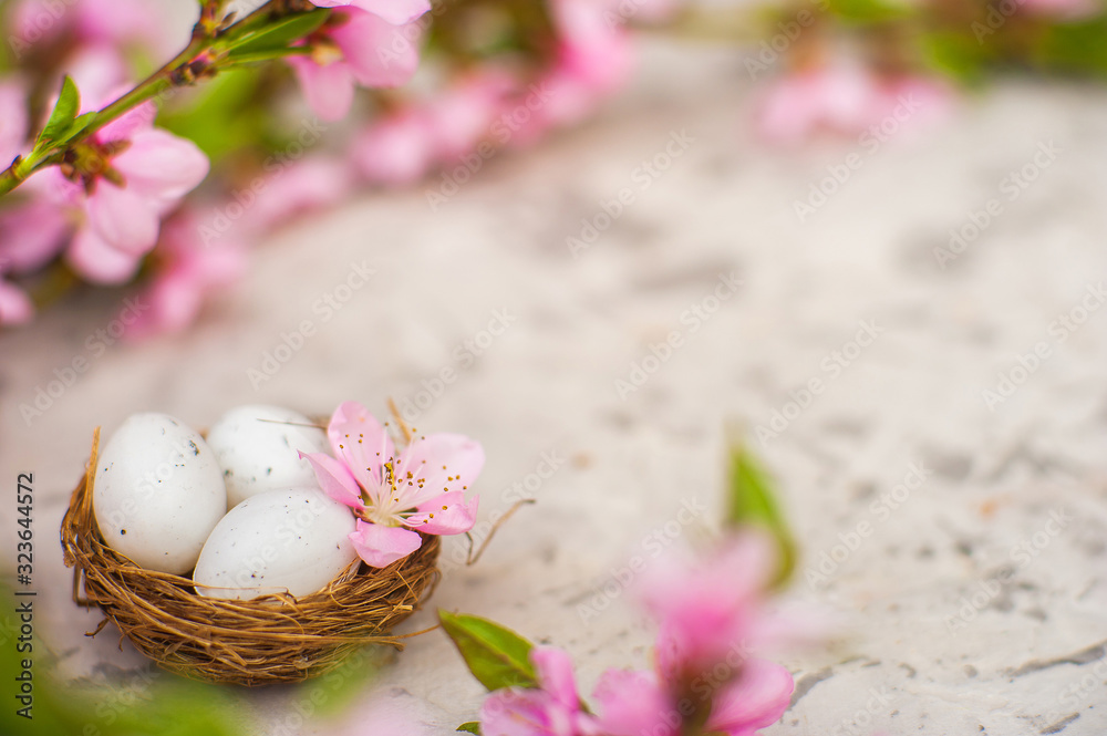 The concept of spring Easter card. Eggs in the nest and flowering branch in pink colors close-up and copy space.