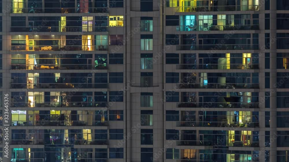 Rows of glowing windows with people in the interior of apartment building at night. Modern skyscraper with glass surface. Concept for business and modern life. Zoom out Rows of glowing windows with people in the interior of apartment building at night. Modern skyscraper with glass surface. Concept for business and modern life. Zoom out
