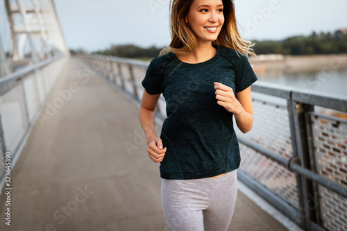 Beautiful fit happy runner woman crossing bridge