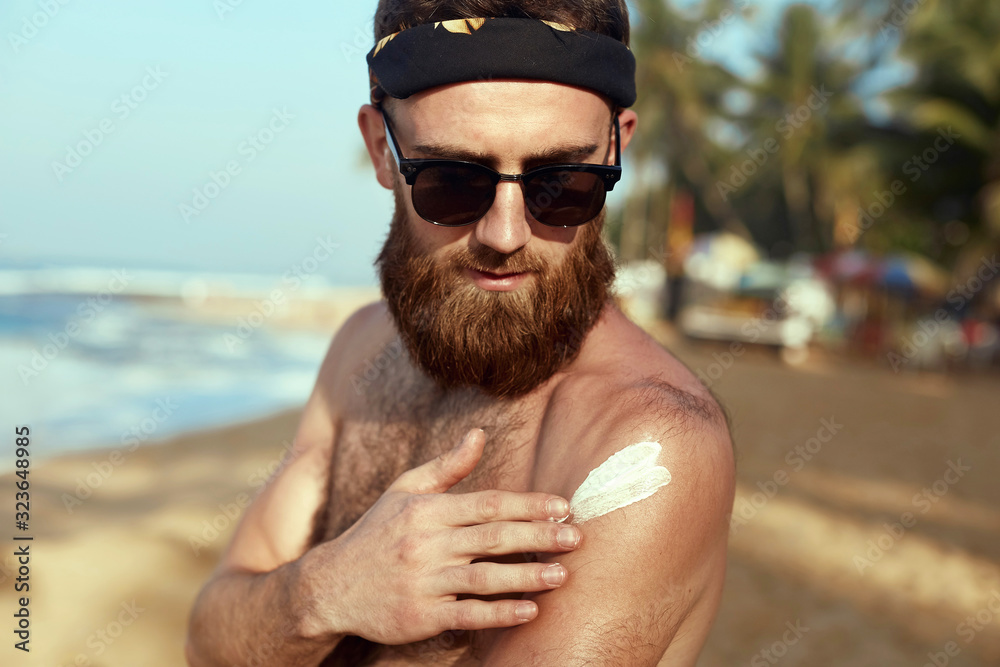 Handsome Man with beard, In Sunglasses Sunbathing With Sunscreen Lotion Body In Summer. Male Fitness Model Tanning Using Solar Block Cream For Healthy Tan. Skincare. Sun Skin Protection Handsome Man with beard, In Sunglasses Sunbathing With Sunscreen Lotion Body In Summer. Male Fitness Model Tanning Using Solar Block Cream For Healthy Tan. Skincare. Sun Skin Protection