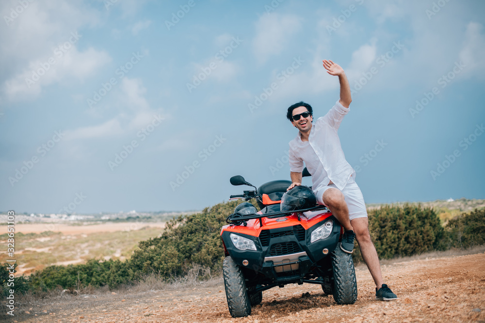 A man with a helmet in his hands next to the ATV A man with a helmet in his hands next to the ATV