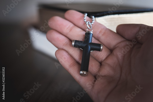 The crucifix lay on the palm of the hand,Bible background And close-up images of praying for the blessing of Jesus, God. Faith in the sacred power of God through prayer to Him, Christianity, Jesus.