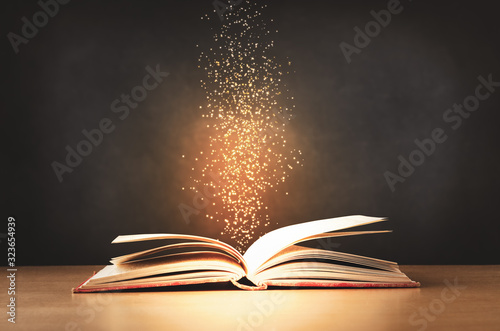 Canvas Print Old Book Opened on Desk with Sparkling stars Rising Upwards