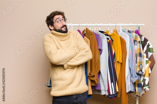 young cool berded man with clothes against flat wall photo