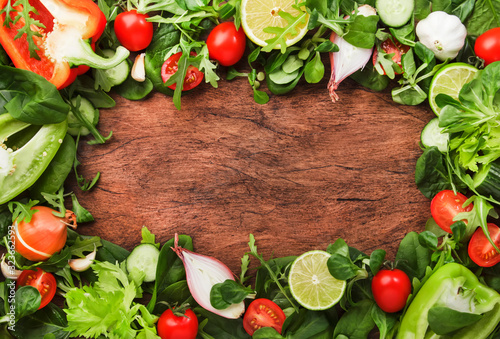 Healthy food background with various green herbs and vegetables. Ingredients for cooking salad. Vegetarian and vegan food concept. Top view  wooden frame with copy space