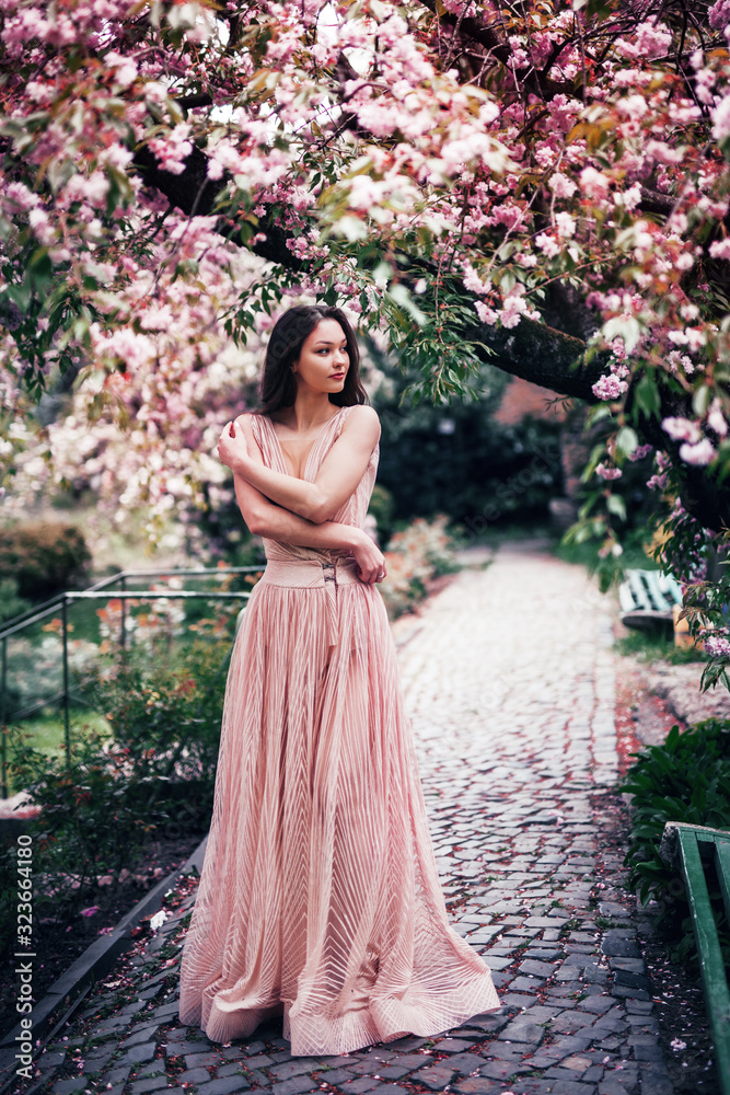 romantic girl stands in a flowering garden hugging herself