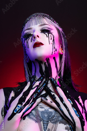 Colorful portrait of a young gothic woman crying with black blood photo