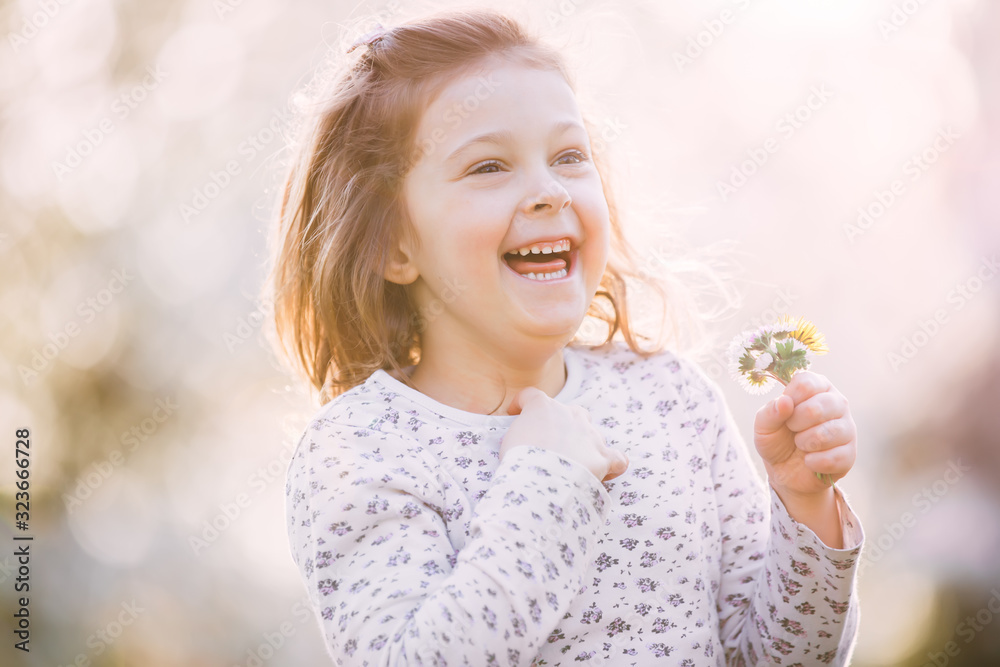 Happy little girl in a blooming spring park with a small field bouquet Happy little girl in a blooming spring park with a small field bouquet