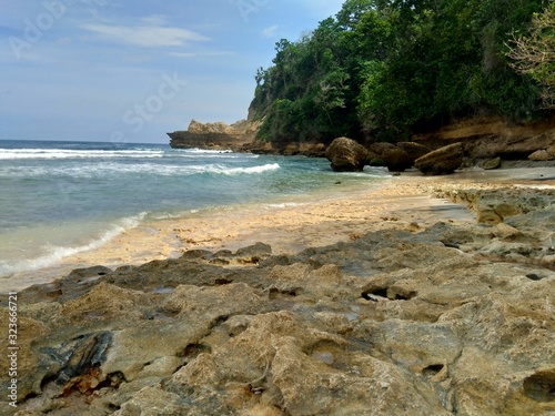Beach with rocks, waves and blue sky. The beautiful Sanggar beach in Tulung Agung, East Java, Indonesia.