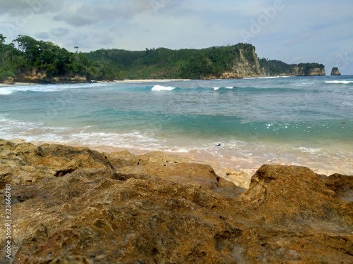 Beach with rocks, waves and blue sky. The beautiful Sanggar beach in Tulung Agung, East Java, Indonesia. photo