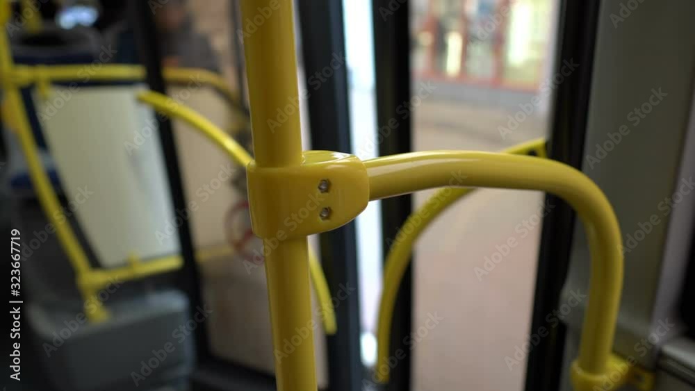 The bus doors close and the bus pulls away from the stop. Close-up of the yellow handrail. View from inside the bus. Blurred background. 4K. The bus doors close and the bus pulls away from the stop. Close-up of the yellow handrail. View from inside the bus. Blurred background. 4K.