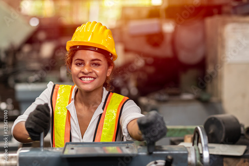Girl teen worker with safety helmet happy smiling working labor in industry factory with steel machine.