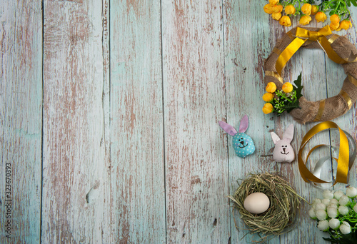 Easter composition. Making an Easter wreath. Blank for a wreath wrapped in burlap  a nest with an egg  cute handmade Easter bunnies  flowers  ribbons and a bow on a wooden background. Free space.