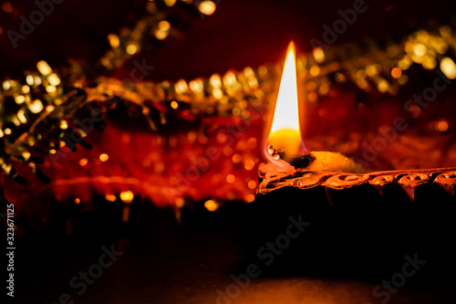 glowing terracotta lamp with golden and red chunni in the background. diwali concept photo