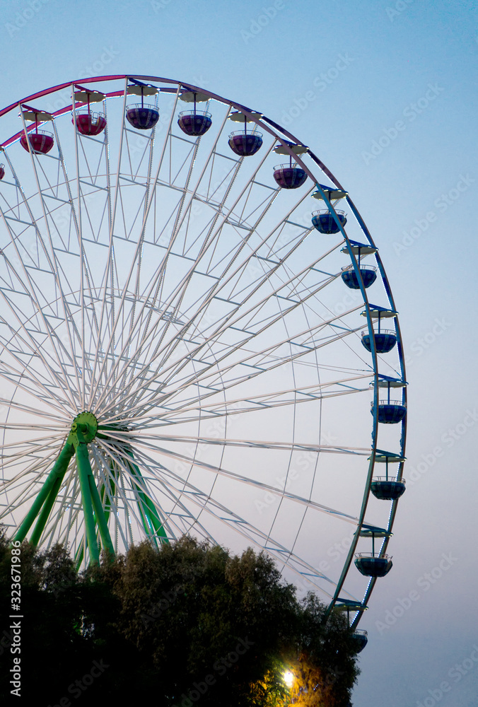 Colorful ferris wheel in the city park at evening.