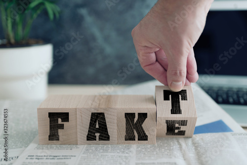 FAKE or FAKT, German for fact, on wooden blocks on newspaper, real news or fake news concept photo