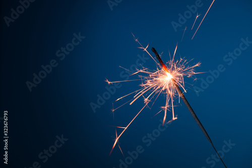 Burning sparkler bengal fire on blue background