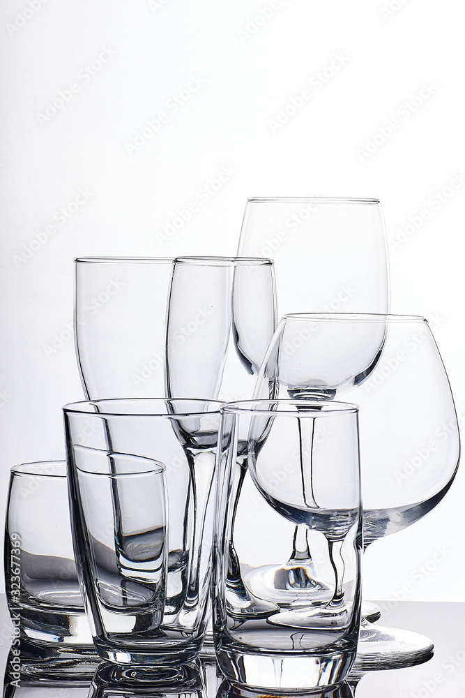 set of glass empty glasses and goblets on a gray-white background set of glass empty glasses and goblets on a gray-white background