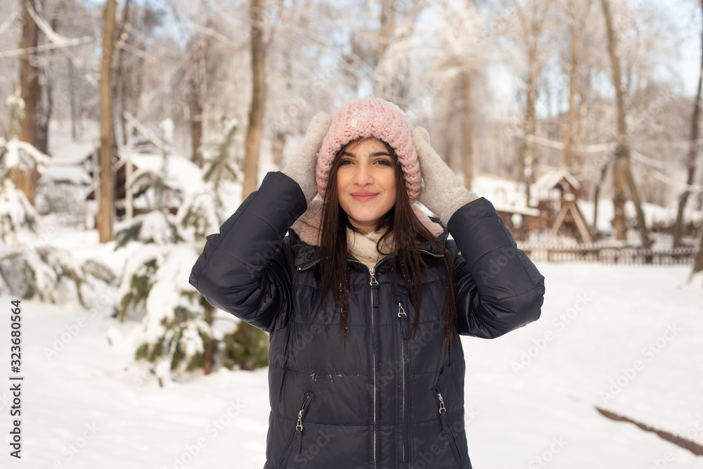 Beautiful woman standing among snowy trees in winter forest and enjoying first snow Beautiful woman standing among snowy trees in winter forest and enjoying first snow