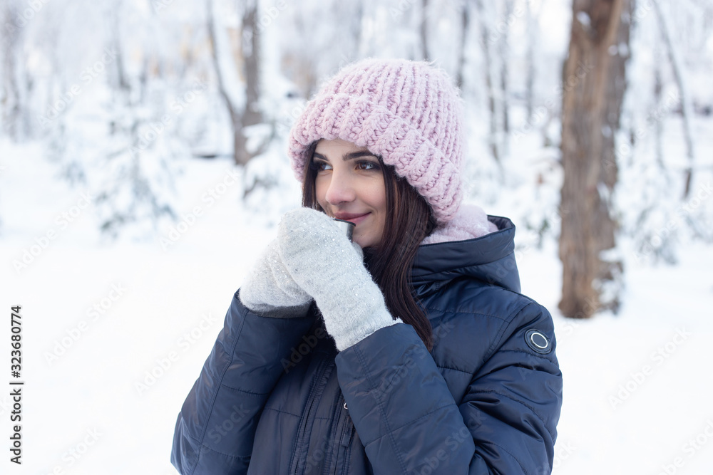 Young woman with hot tea cup in snowy park in winter