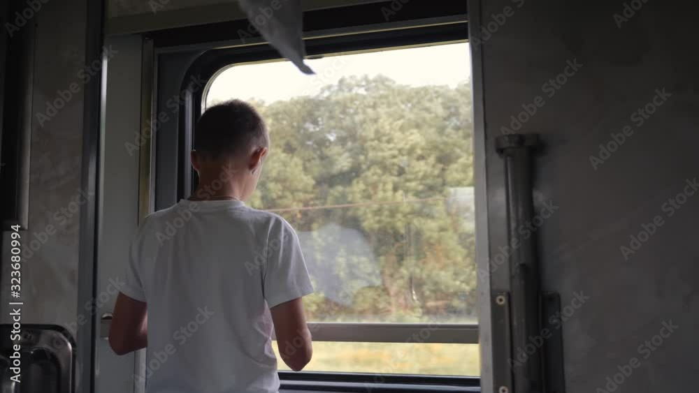 The boy looks out the window of the train car. Family travel with children. The boy looks out the window of the train car. Family travel with children.