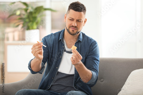 Emotional man with nicotine patch and cigarette at home photo