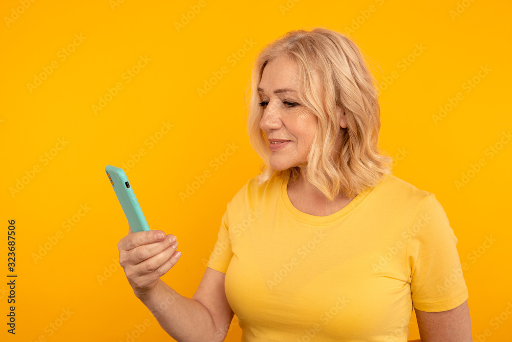 Pretty adult lady in bright clothes watching camera and posing with blue phone Pretty adult lady in bright clothes watching camera and posing with blue phone