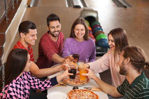 Photography Group of friends with drinks and pizza in bowling club