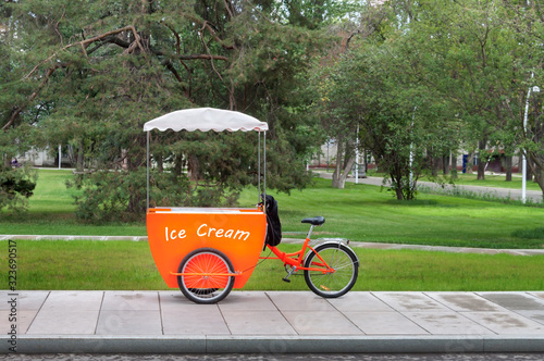 Ice cream orange truck green city park tree background warm sunny summer or spring day