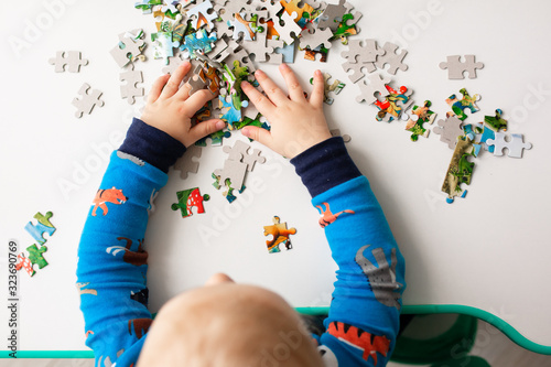 Baby boy solving jigsaw puzzle on the desk