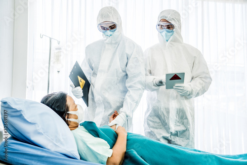 Fotografia Doctors in the protective suits and masks are examining the infected aging femal