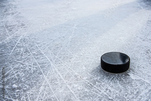 black hockey puck lies on ice at stadium