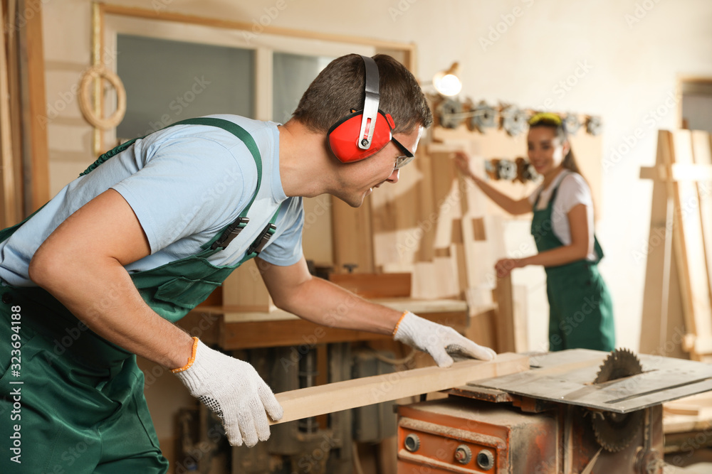 Professional carpenter with wooden plank in workshop
