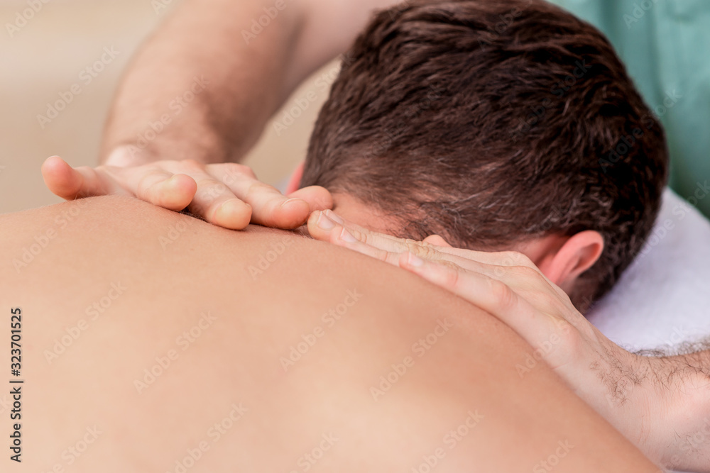 Young man receiving back massage, close up.