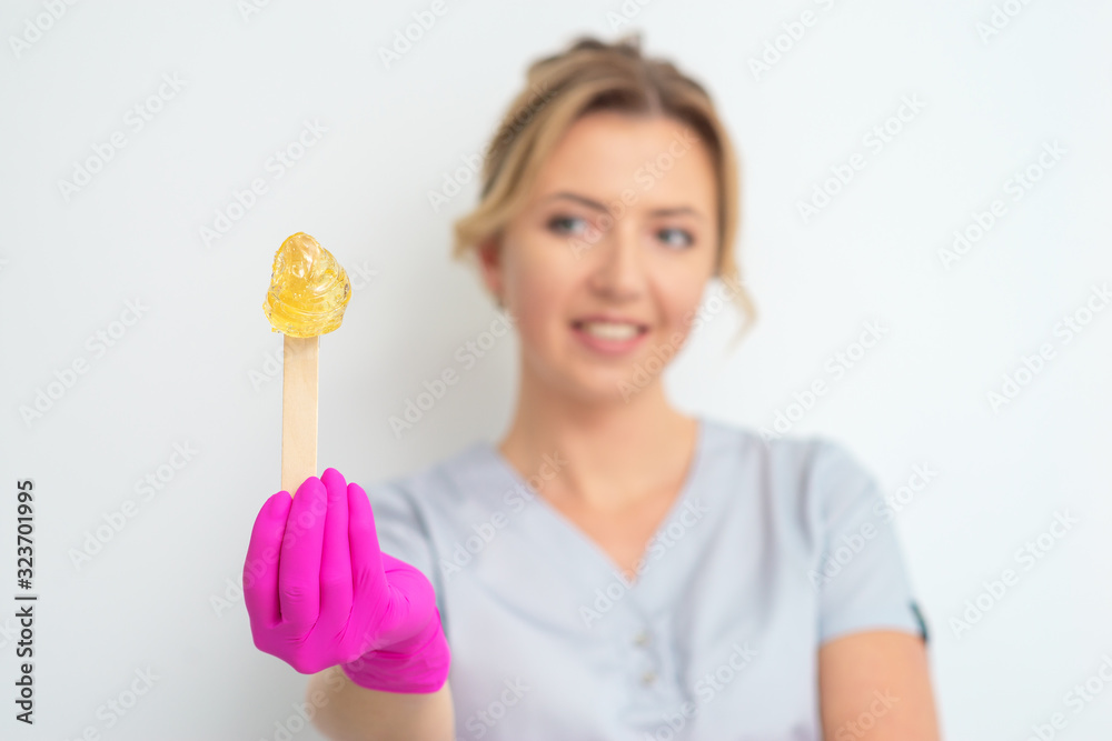 Stick with wax for epilation in beautician's hand on white background. Stick with wax for epilation in beautician's hand on white background.