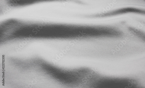 White linen bed sheet material, empty wrinkled fabric pattern. Crumpled bedding surface, horizontal white background close up top view 