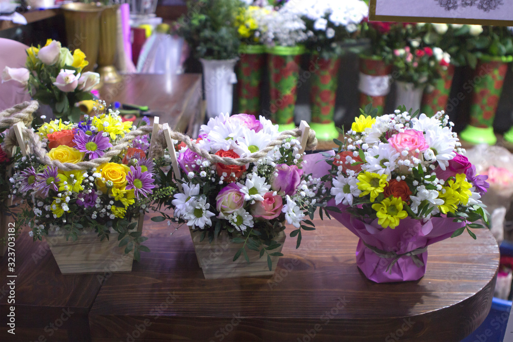 bouquets with flowers on the counter of a flower shop. Roses, chrysanthemums and alstroemeria in wooden vase boxes