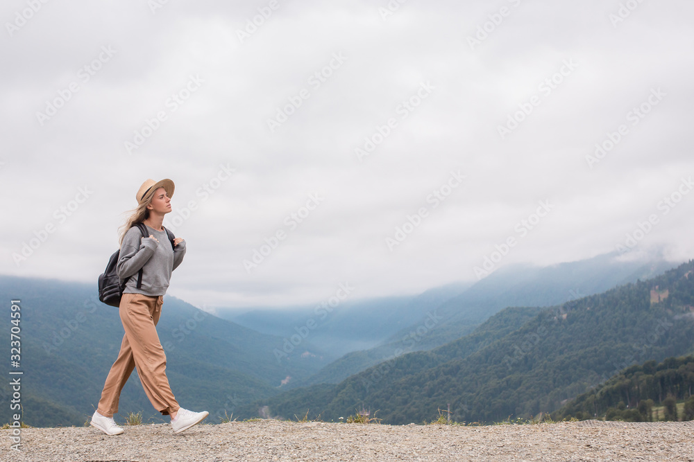 Side view slim young caucasian girl walks on top of mountain. Youth and discovery, thirst for travel. Female Student Blogger Enjoys Mountain Vacation. Togetherness With Nature And Relaxation Concept Side view slim young caucasian girl walks on top of mountain. Youth and discovery, thirst for travel. Female Student Blogger Enjoys Mountain Vacation. Togetherness With Nature And Relaxation Concept
