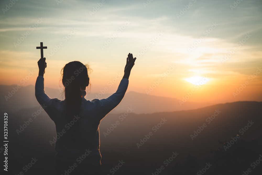A women is praying to God on the mountain. Praying hands with faith in religion and belief in God on blessing background. Power of hope or love and devotion. - obrazy, fototapety, plakaty 