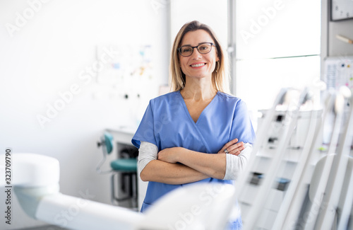 A portrait of dental assistant in modern dental surgery, looking at camera. photo